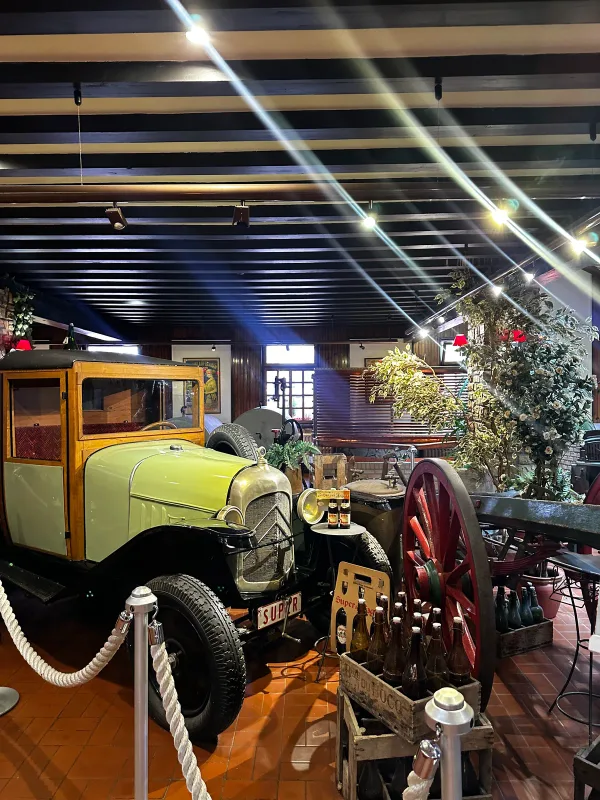Automobile ancienne dans un intérieur aux poutres sombres et au sol en terre cuite.